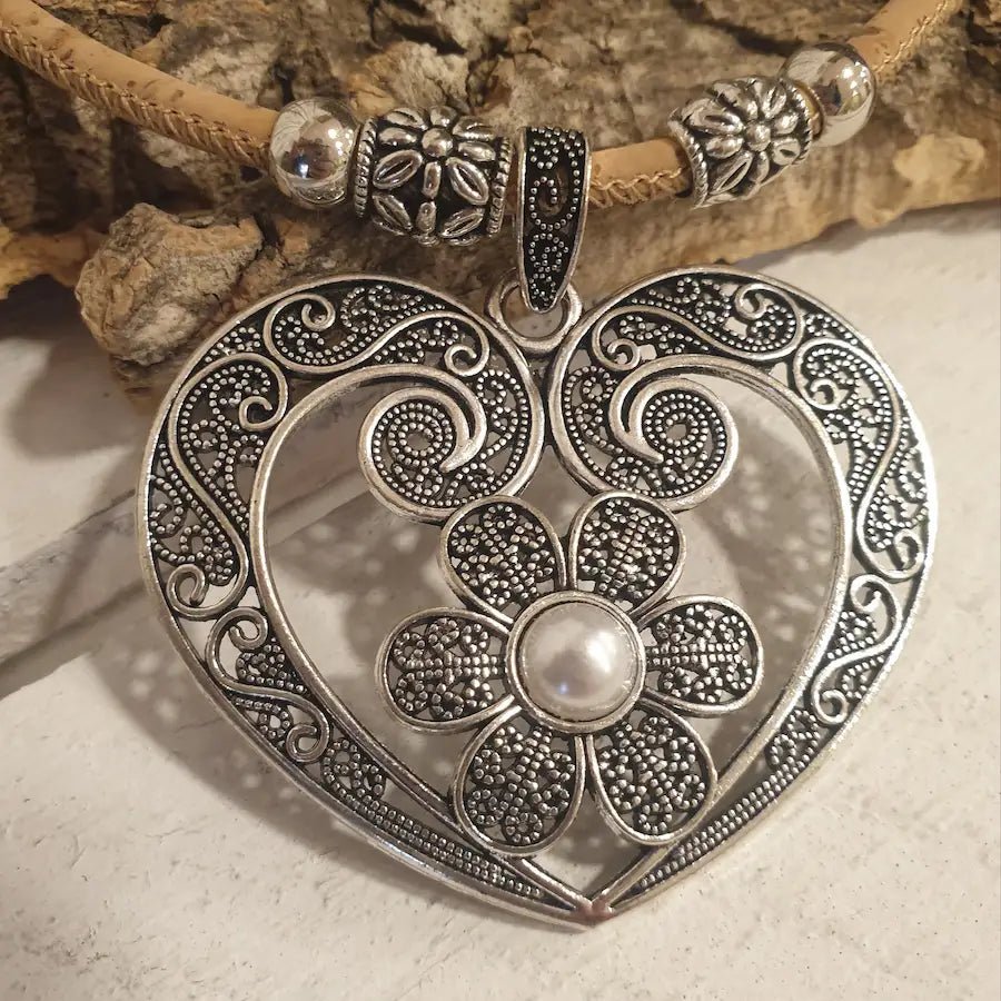 Détail du pendentif cœur avec fleur et perle centrale